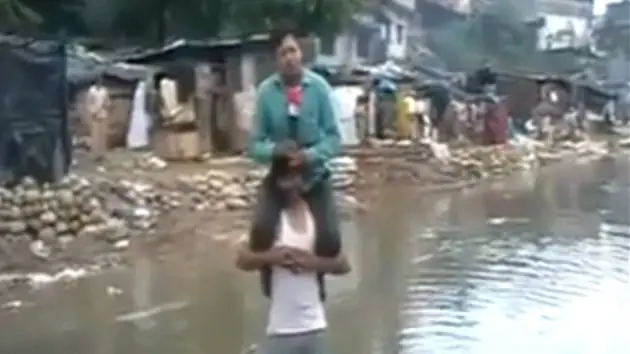 Reportero cubre noticia sobre los hombros de un damnificado